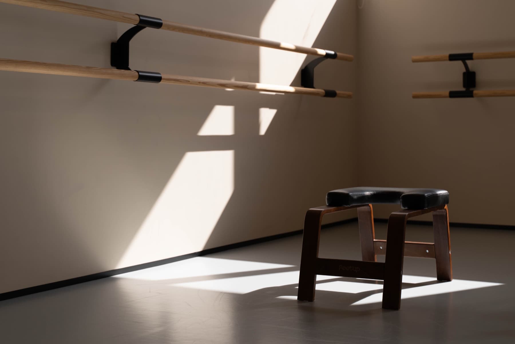 Estúdio Solo banhado pela luz da janela, barras de ballet e um banco de pilates.
